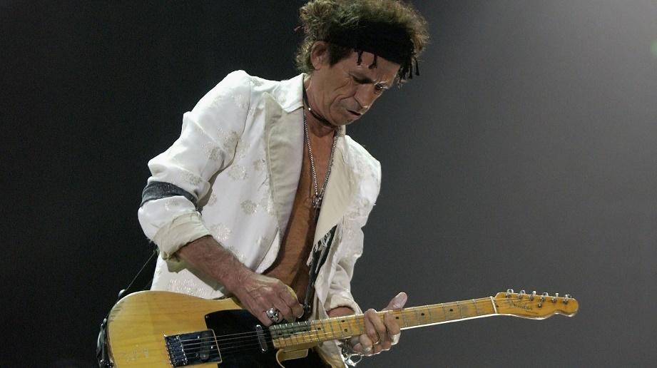 Keith Richards in white with wooden guitar