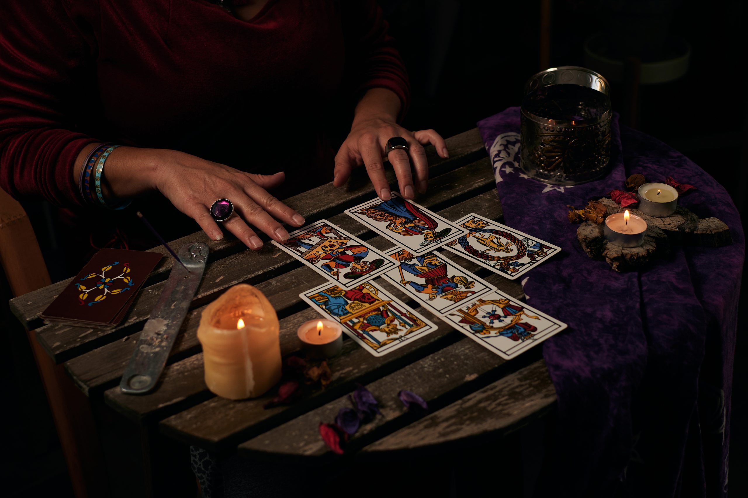 pythoness reads tarot cards table with candles scaled