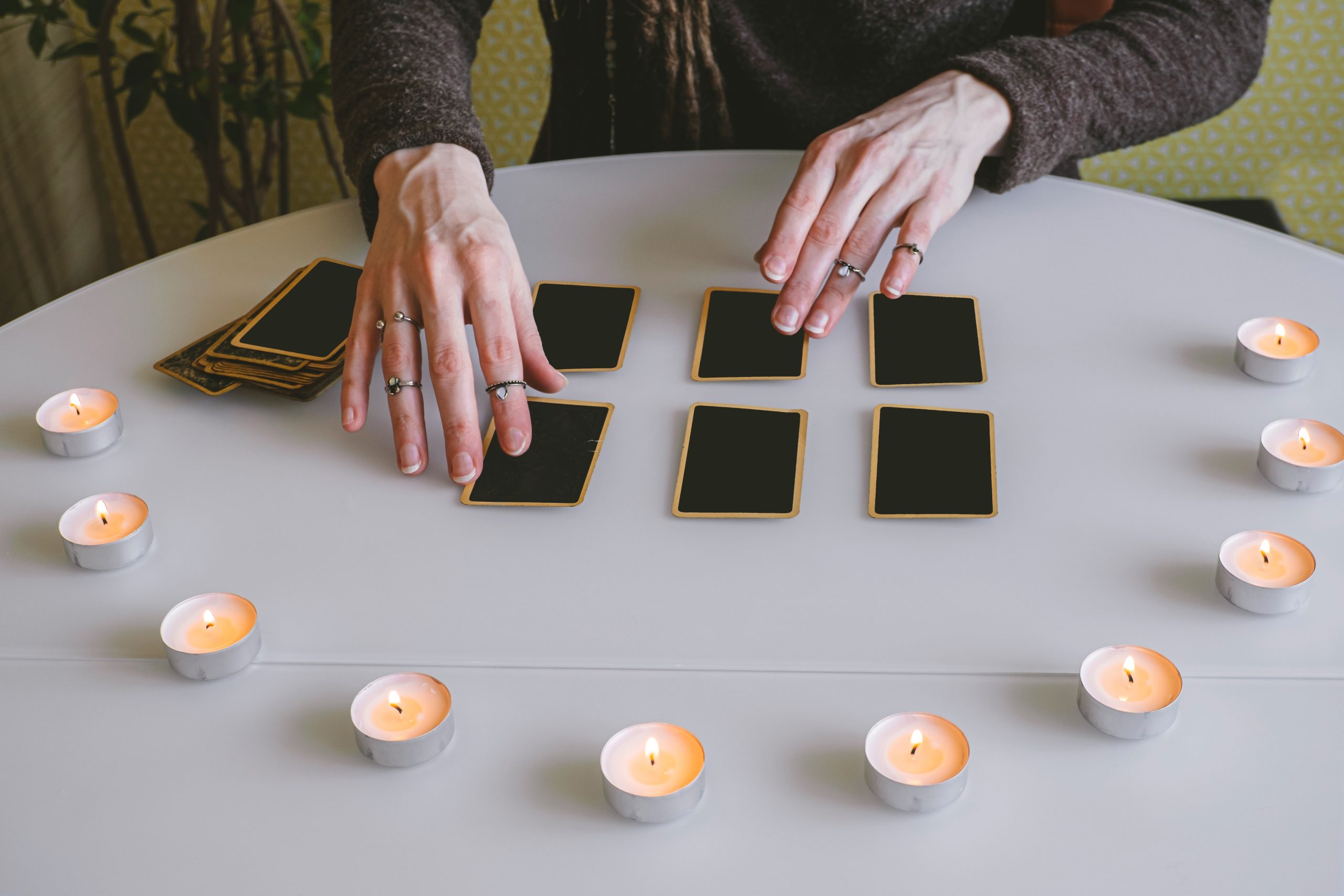 young woman lays out black cards table with candle lights scaled